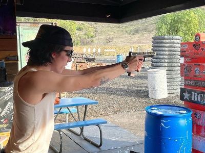 Quinn Welliver is on his vest with a cap and specs as aiming with his gun.